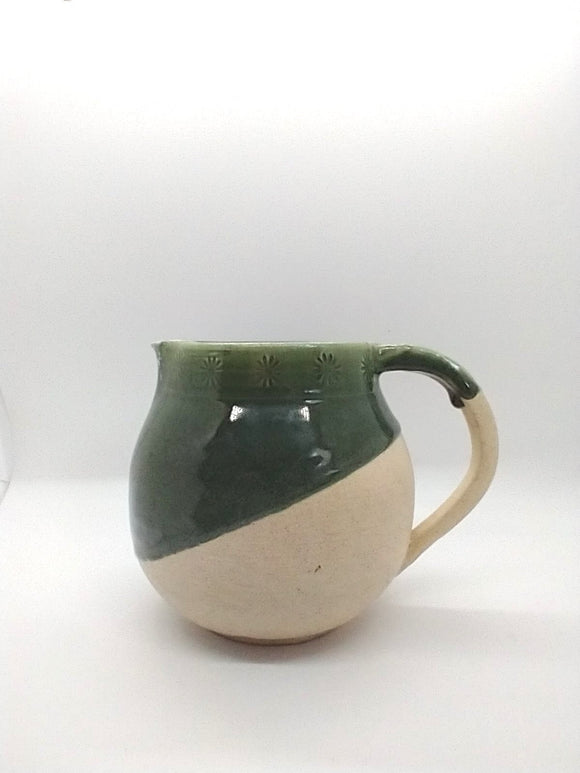 Round green and white ceramic pitcher decorated with floral engravings