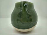 Front view of round green and white ceramic pitcher decorated with floral engravings