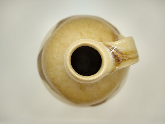 Top view of a gold and white glazed vessel with a handle